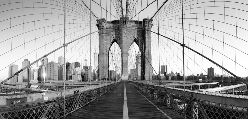 A black and white image featuring the New York City skyline with the Brooklyn Bridge