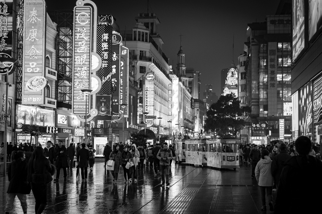 A black and white image showing people walking along the street in Shanghai